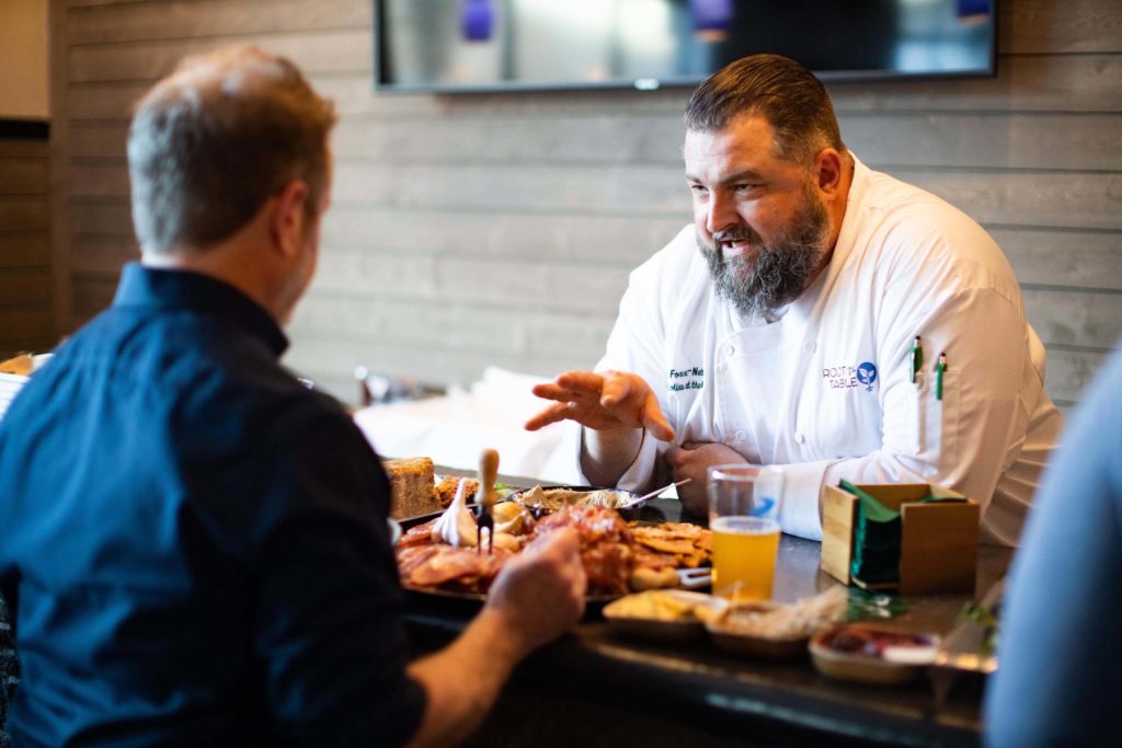Chef Erik Foxx-Nettnin talking with a guest at 2019 Root to Table VIP event